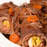olives mushrooms and onions rolled up in beef topped with onions and carrots.