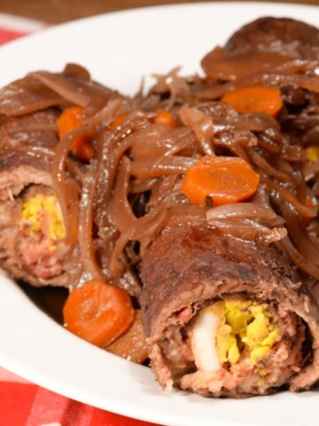 olives mushrooms and onions rolled up in beef topped with onions and carrots.