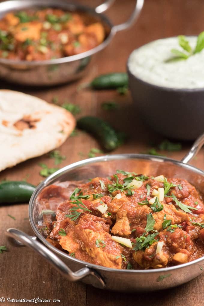 chicken karahi in a bowl with naan bread and raita 