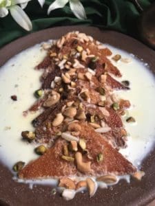 a plate of shahi tukra fried bread covered with milk and nuts