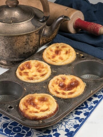 4 beautiful pais de nata custard tarts in a muffin pan.