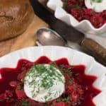 A bowl of Russian borsht with a scoop of sour cream and garnished with dill