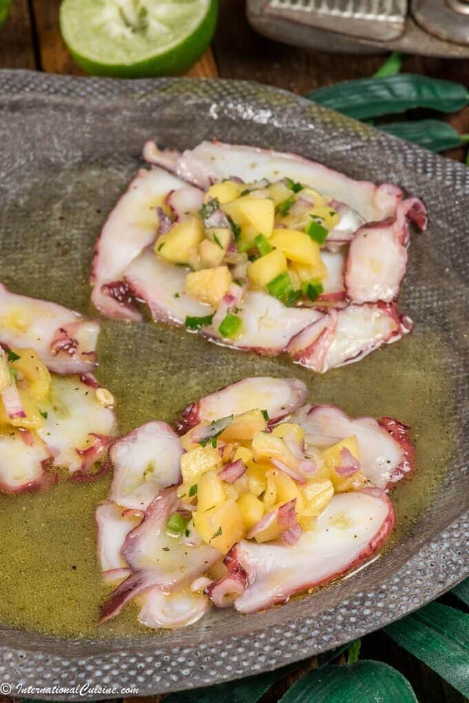 a plate of octopus carpaccio topped with mango salsa