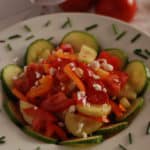 a bowl of Serbian salad with cucumbers, tomatoes, peppers and cheese