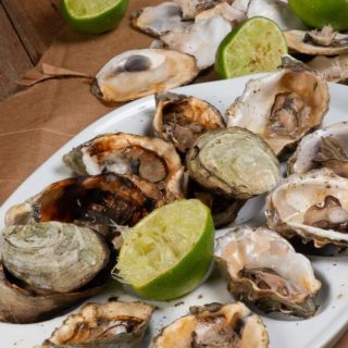 a plateful of freshly grilled oysters with squeezed lime