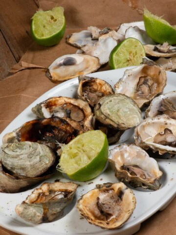 a plateful of freshly grilled oysters with squeezed lime