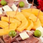 A plate full of Proscuitto, cheese and melon