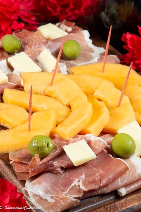 A plate full of Proscuitto, cheese and melon
