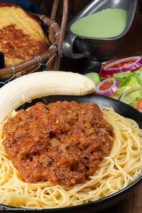  Une assiette pleine de pâtes garnies de sauce pour pâtes somalienne appelée suugo avec une banane.