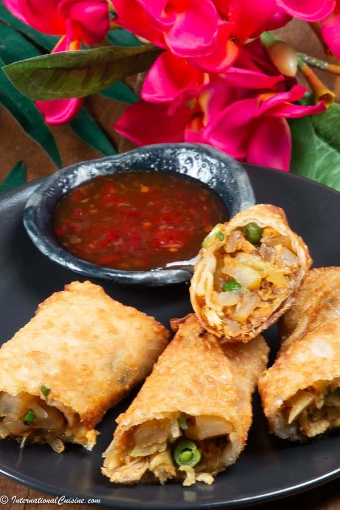 A plateful of Surinamese Spring rolls called loempia surround a sweet chili dipping sauce.