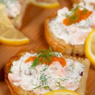 A plateful of Toast Skagan, shrimps in a mayonaise mixture topped with caviar, garnished with dill and a thin slice of lemon.