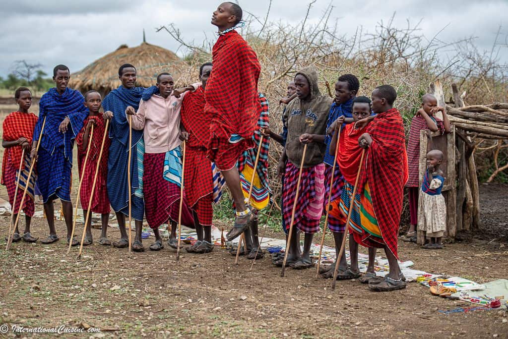 a Massai tribe dancing with one jumping high in the air in their colorful bright dress. 