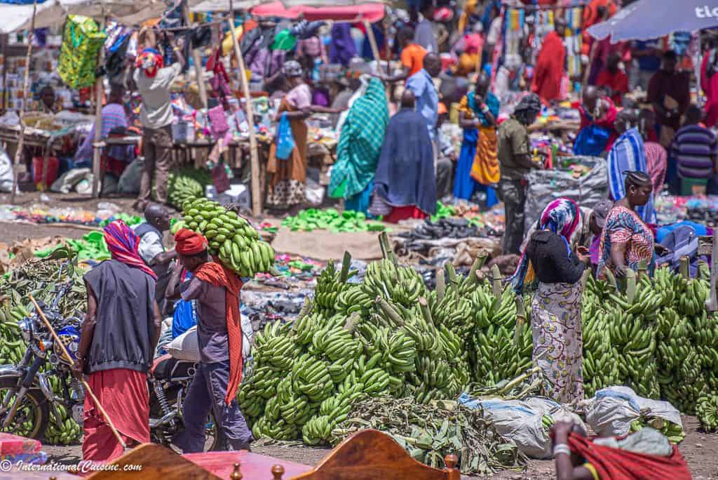 A very busy African market selling giant bushels of green bananas