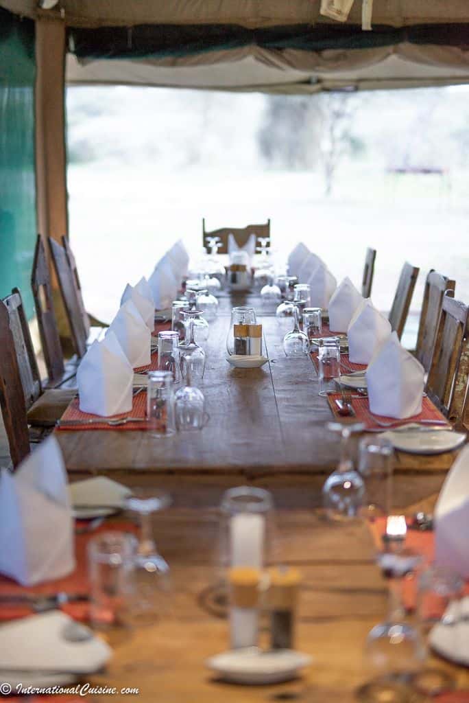 A dining tent on the Serengeti beautifully set with white linens and candles