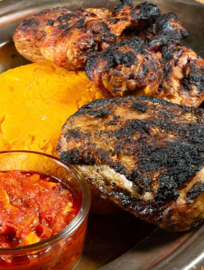 A plateful of Togolese grilled chicken served with djenkoume, a tomato cornmeal