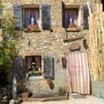 a picture of the front of Osteria Senz'Oste a stone house with a curtain and blue shutters