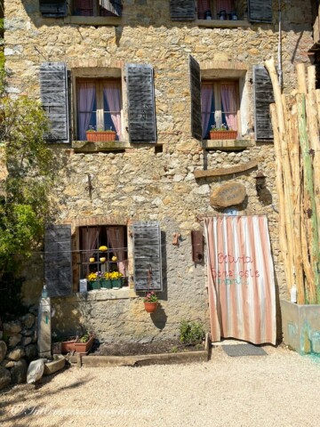 a picture of the front of Osteria Senz'Oste a stone house with a curtain and blue shutters