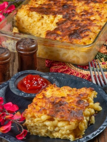a plate with a big square of Macaroni pie and Side of ketchup.
