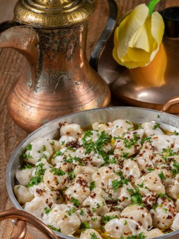 a bowlful of Turkish manti garnished with mint and Aleppo pepper oil