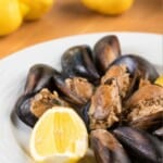 a plate full of Turkish stuffed mussels served with a slice of lemon.