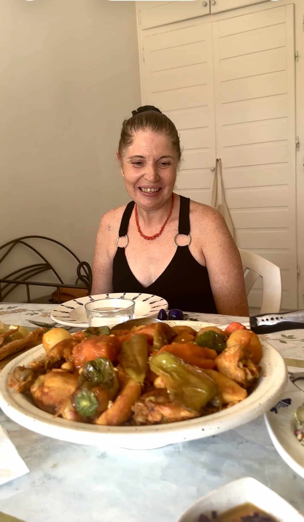 Jiji seated behind a traditional meal during a home cooking experience in Tunis.