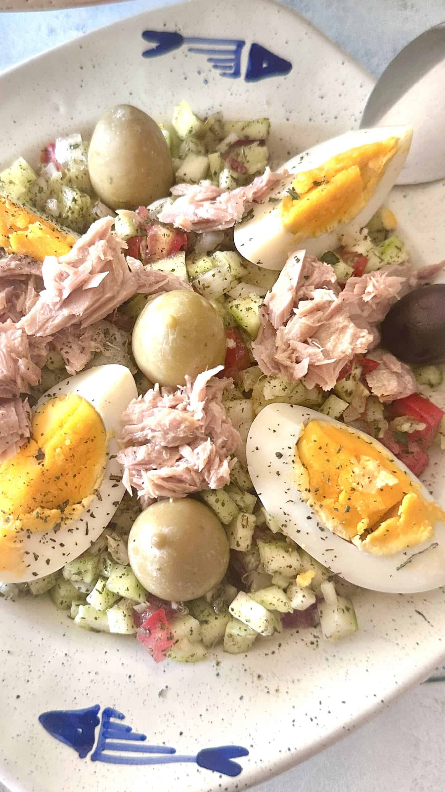 Tunisian salad topped with tuna, hard boiled eggs and green and black olives.